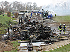 Der Bagger hilft, indem er die verbrannten Gebäudeteile abreißt und auseinanderzieht (Foto: THW / M. Braunst).