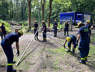 Für den Feldfernkabel-Überbau der Zufahrt richten die Helferinnen und Helfer des Fachzugs FK eine Lattenschere auf (Foto: THW / H. Jarzina).